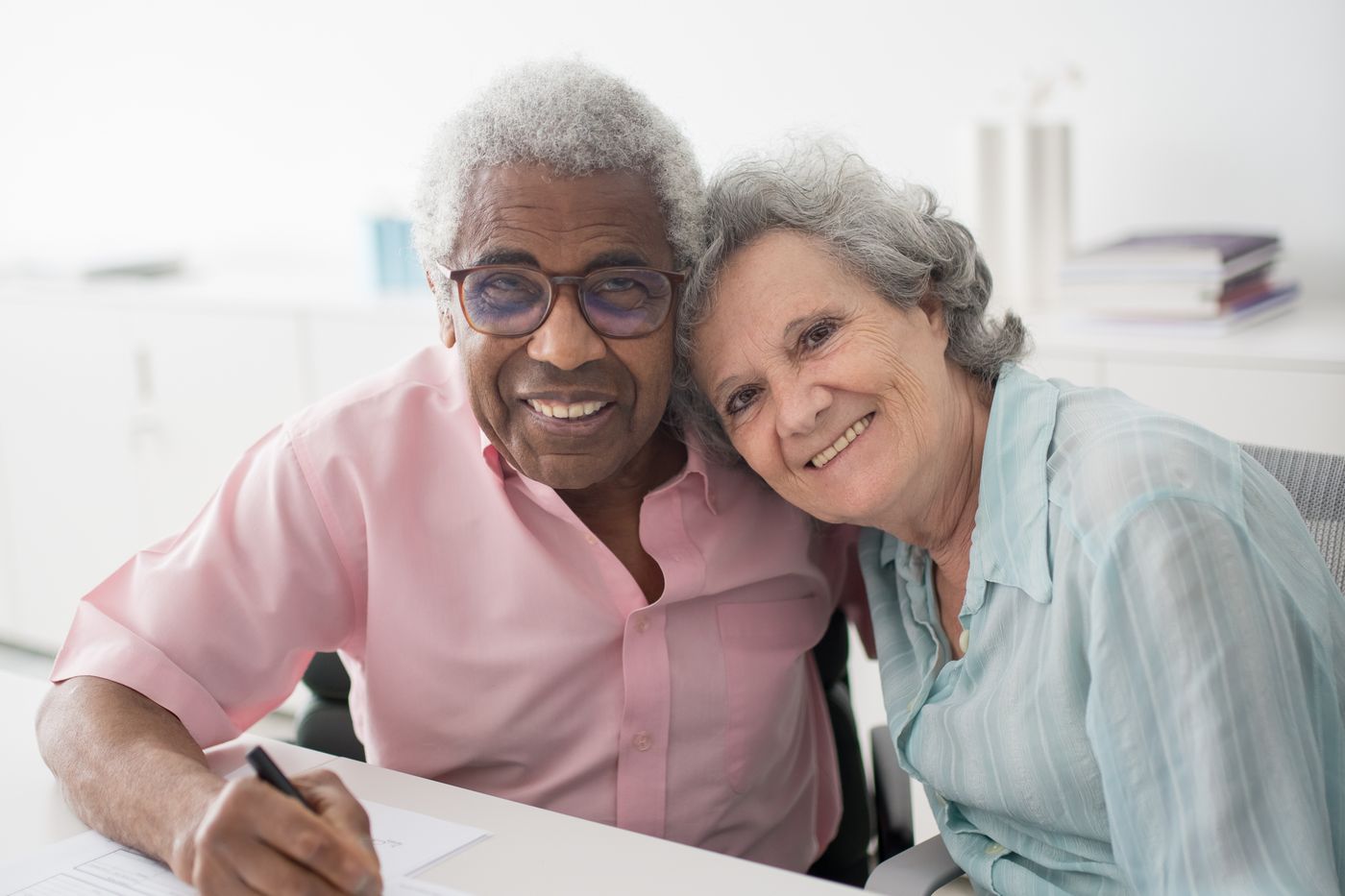 An older Utah couple at a kitchen table reviewing life insurance and retirement account beneficiary paperwork together.