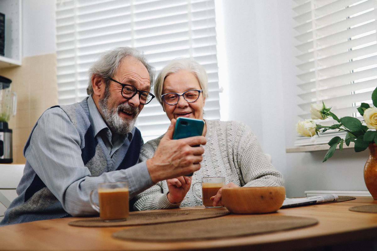 A Utah couple in their sixties sitting at a kitchen table with coffee, checking Medicare and Medicaid coverage details together.