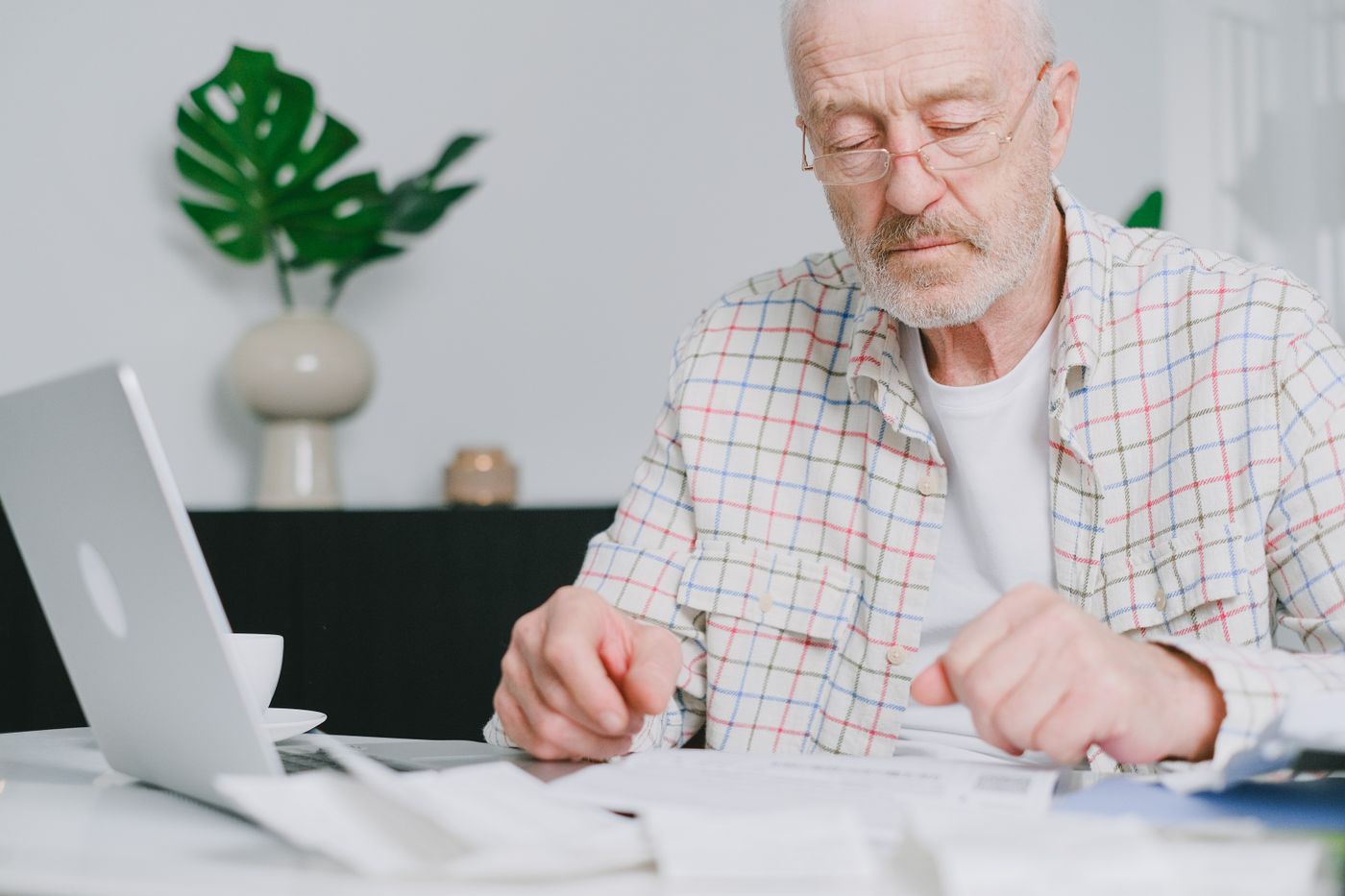 A retired federal employee at a desk at home, glasses on, working through Federal Employees Health Benefits and Medicare enrollment paperwork before deciding about Part B.