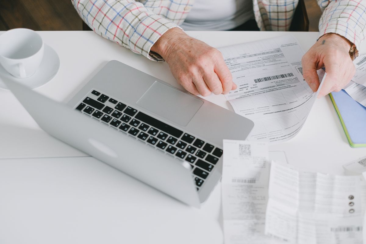 An older Utah retiree's hands sorting Medicare statements and medical bills beside a laptop while weighing a high-deductible Medigap Plan G.