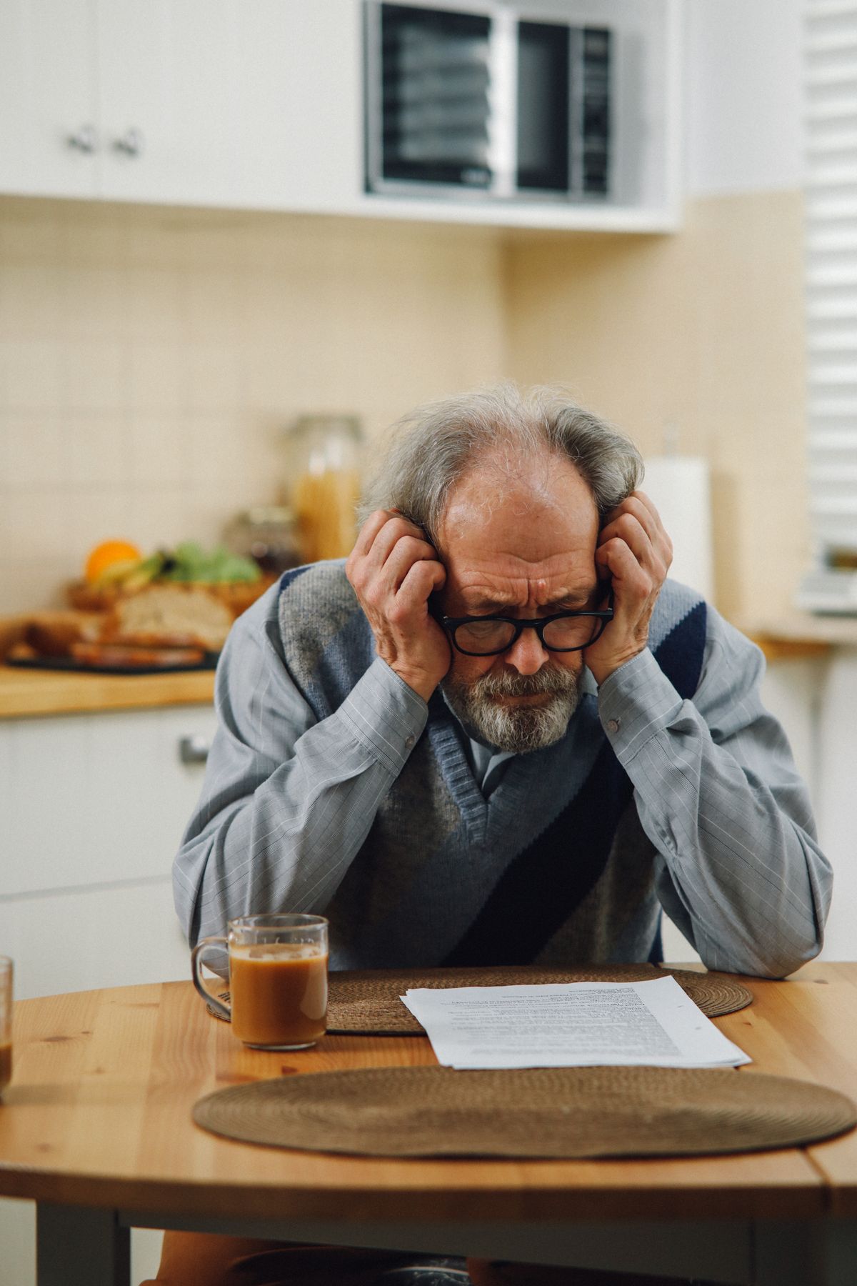 An older Utah man in eyeglasses reads a Medicare Advantage prior authorization letter at his kitchen table, looking concerned.