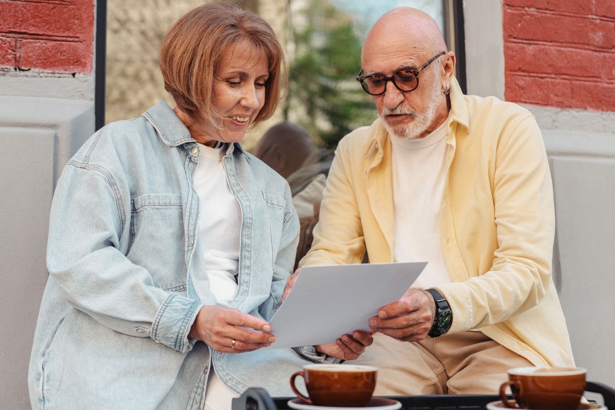 An older couple sits side by side reading a letter together over coffee, the way many Utah retirees review their Medicare Annual Notice of Change when Open Enrollment opens.