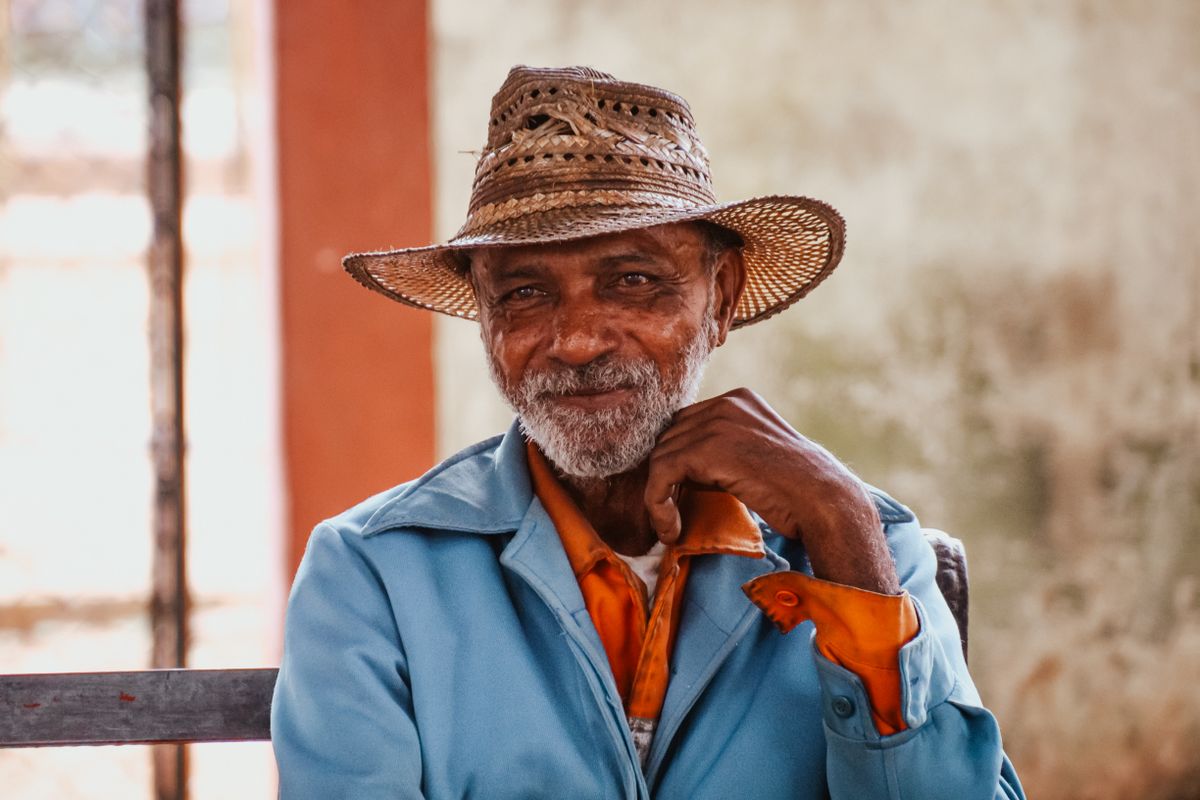 An older man in a wide-brimmed straw hat sits in bright sunlight, the kind of sun protection that matters in Utah, where melanoma rates among people 65 and older are the highest in the nation and Medicare covers skin cancer care after a spot is found.