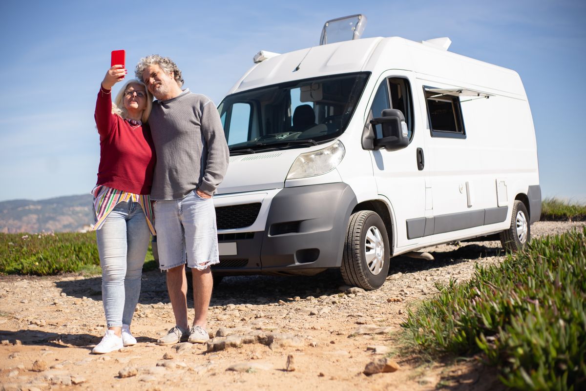 A retired Utah couple standing beside their RV during an extended road trip, the kind of long absence that starts a Medicare Advantage plan's six-month service-area clock.
