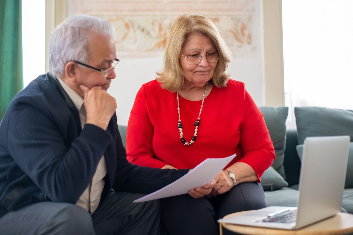 A retired Utah couple sitting together at home reviewing mortgage statements and household financial paperwork before deciding whether to pay off their home loan.