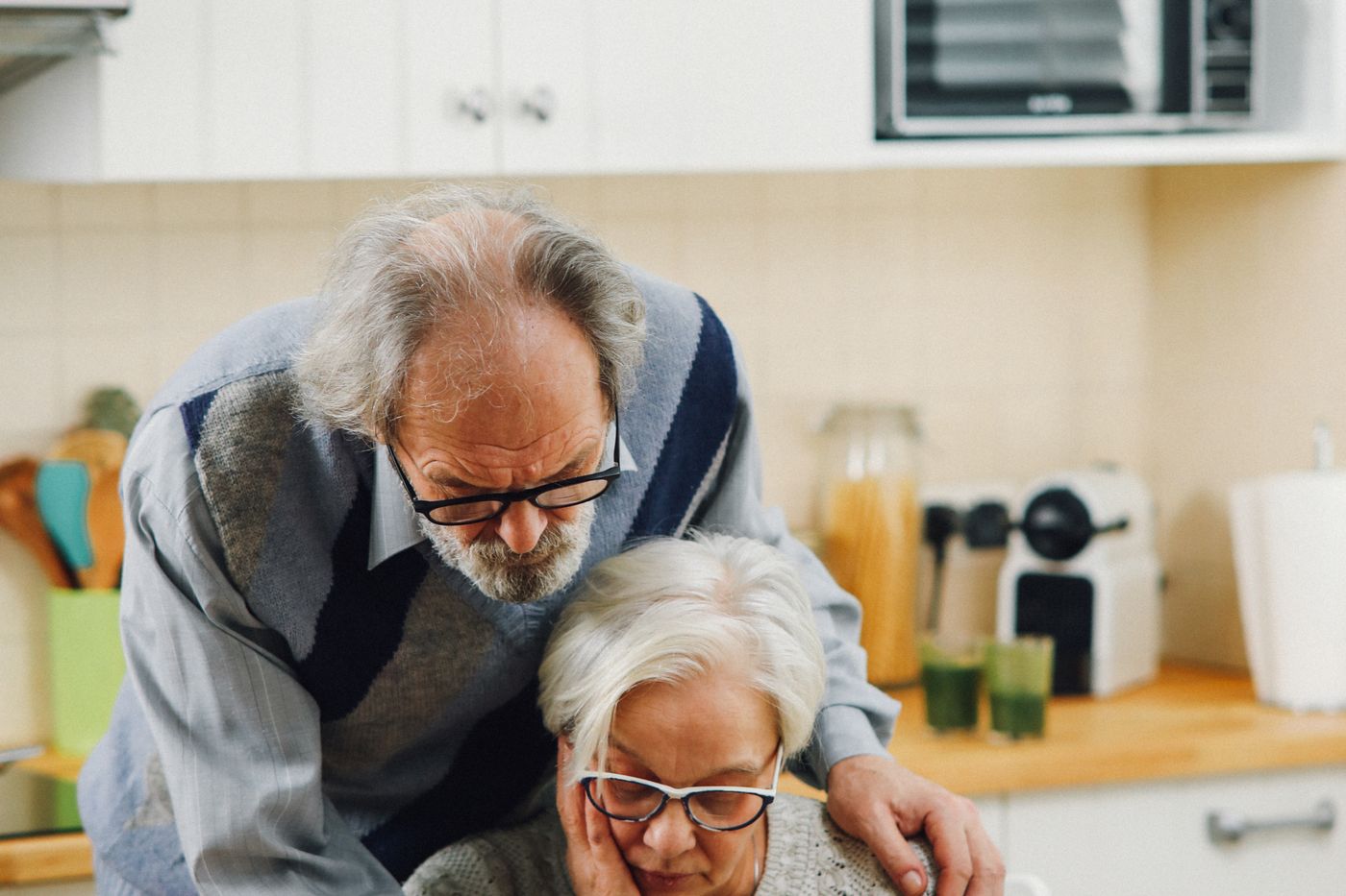 A Utah couple in their early sixties reviewing health insurance and retirement paperwork at their kitchen table before Medicare eligibility.