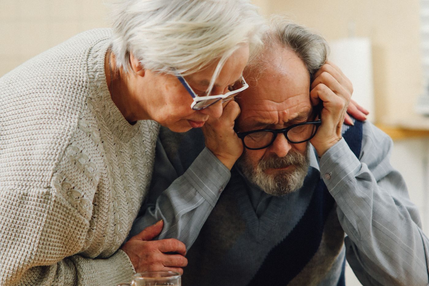 An older Utah couple sitting at a kitchen table reviewing a property tax notice and household paperwork.